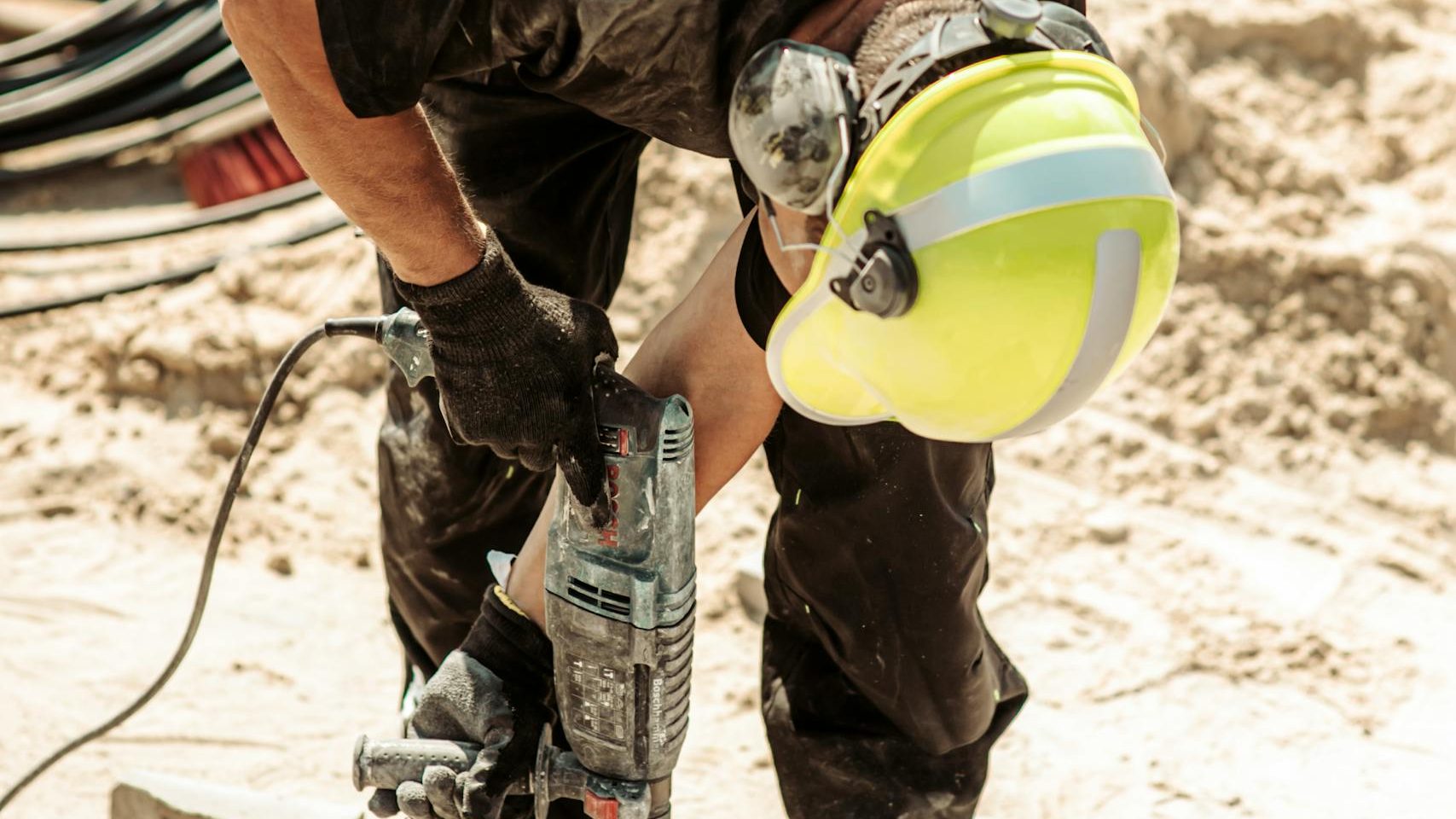 Worker operates a drill on a construction site in Grójec, Poland, showcasing industry.